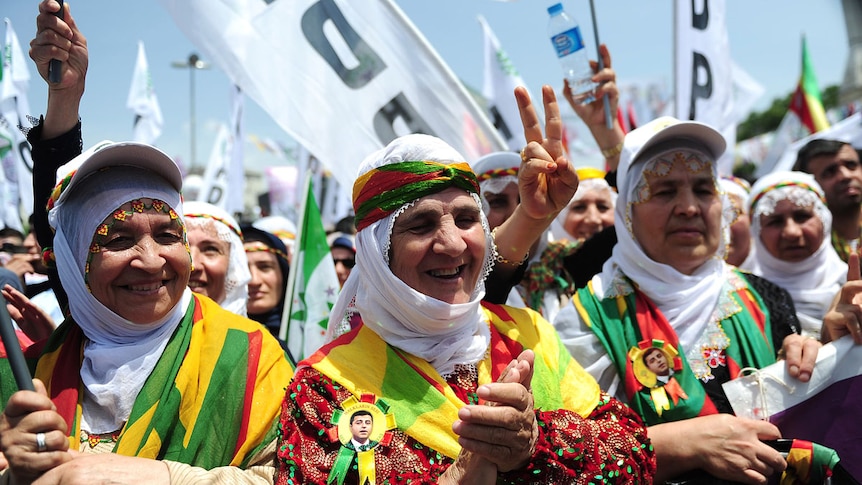 Kurdish women shout slogans and flash victory signs in Istanbul during an election rally