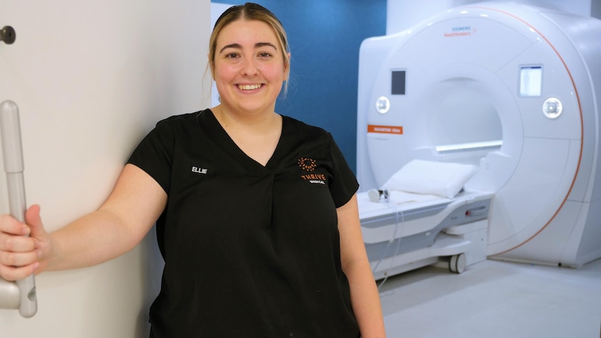 A woman smiling at the door of an MRI machine studio.