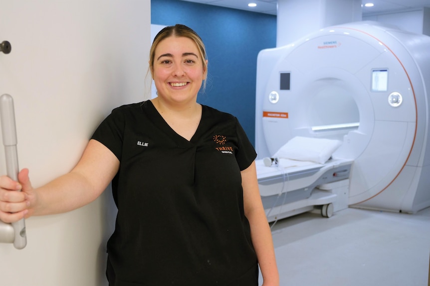 A woman smiling at the door of an MRI machine studio.