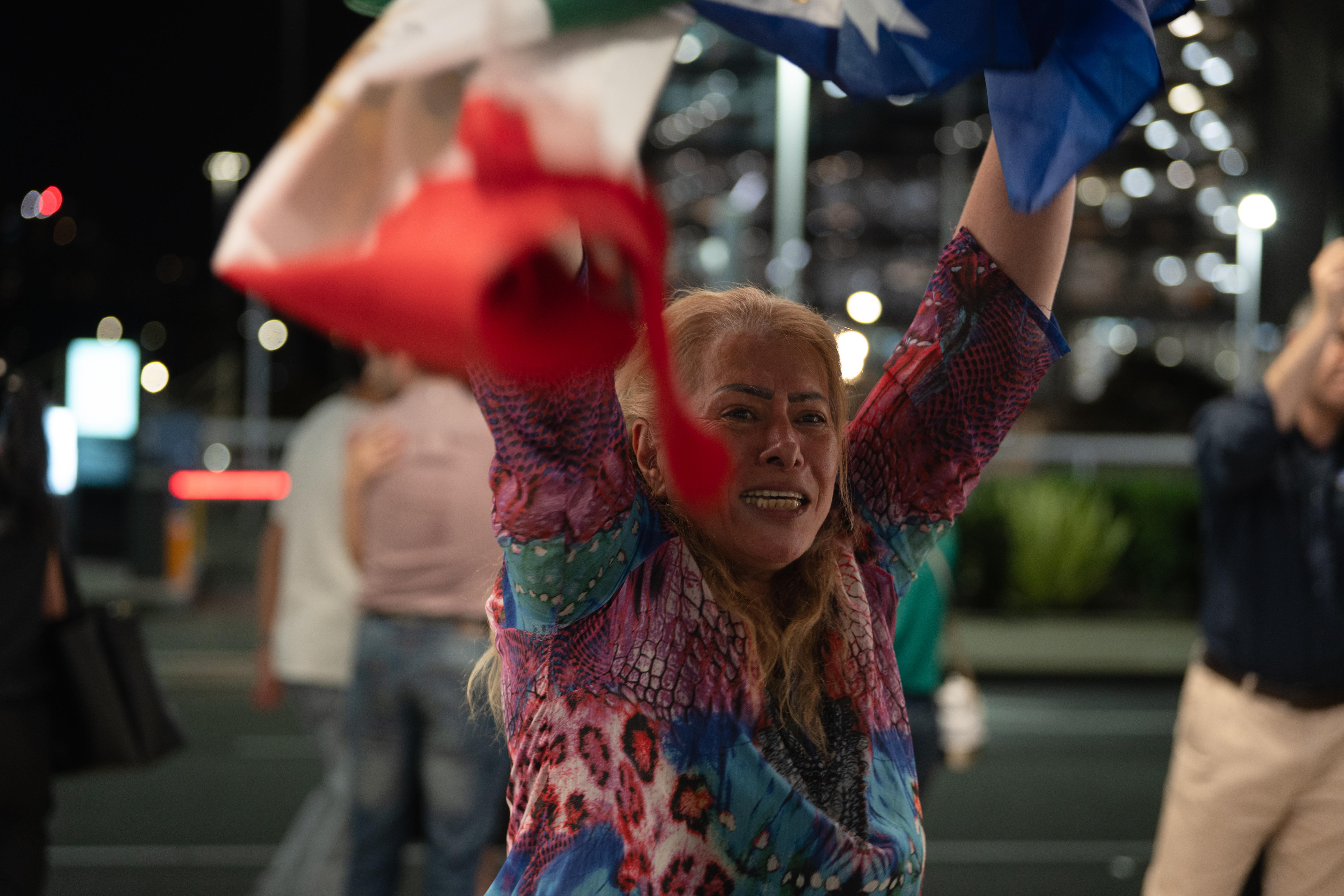 A woman waves flags with arms in the air and a distressed look on her face