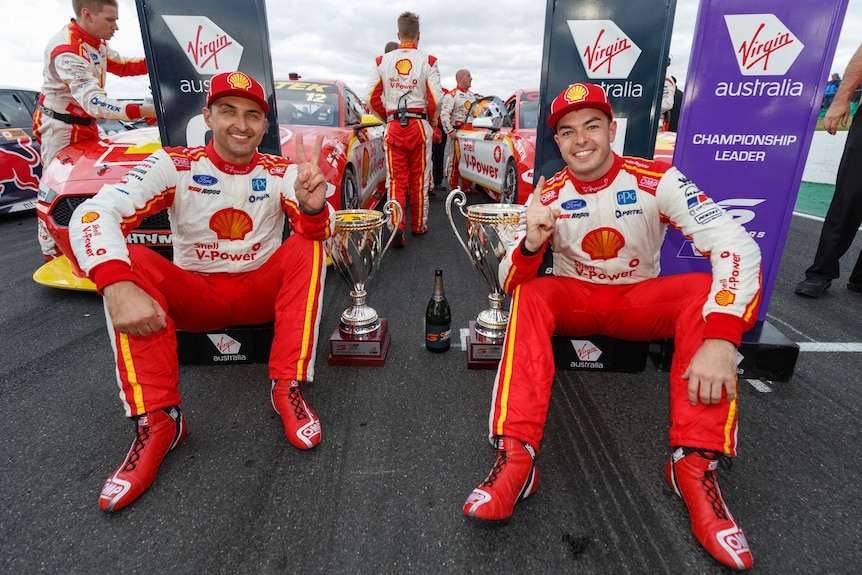 Supercars driver Scott McLaughlin and Fabian Coulthard stick their index fingers in the air.