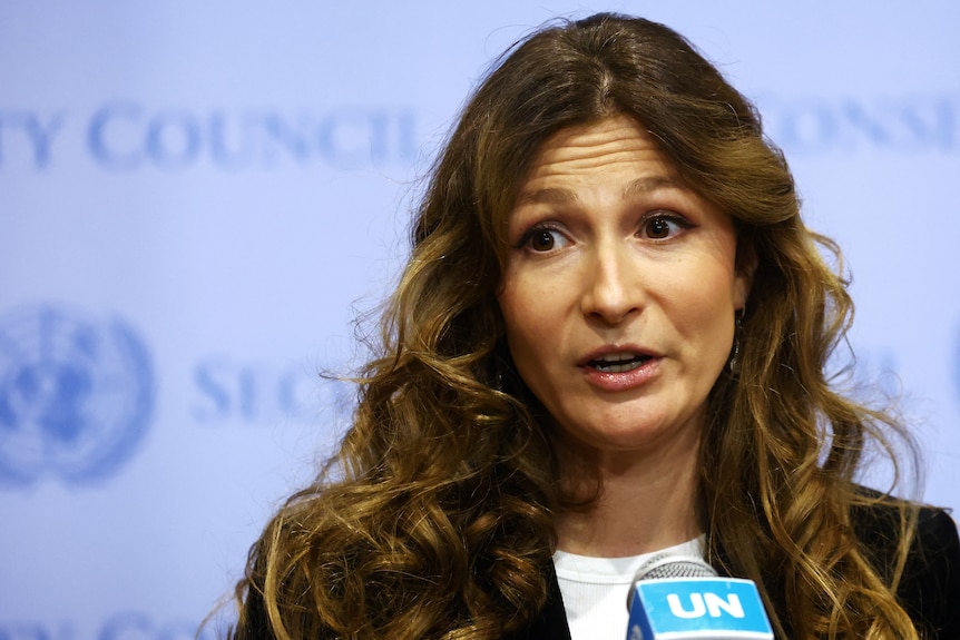 Emine Dzhaparova, a woman with long brown hair, speaks into a UN microphone at a conference.