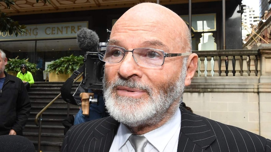 Peter Carr, wearing a suit and glasses, leaves court