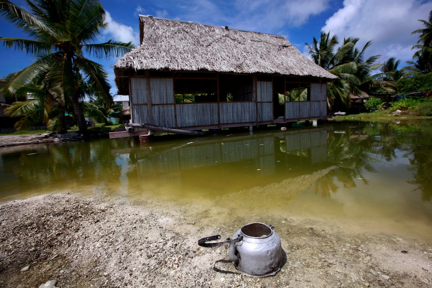 To archiwalne zdjęcie z 2015 roku przedstawia opuszczony dom na wyspie Kiribati na środkowym Pacyfiku, częściowo zanurzony w wodzie morskiej.