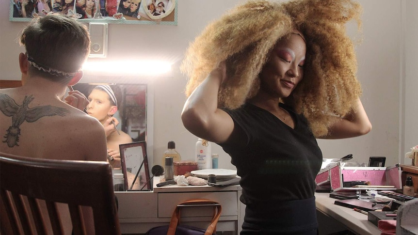 woman in a big fuzzy wig in a changeroom