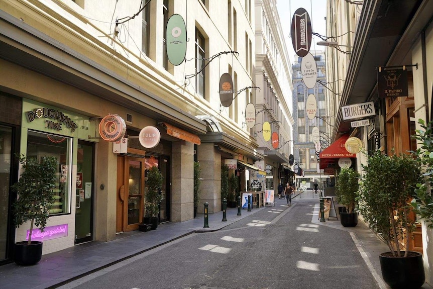 A laneway with closed shops and only two people in the distance.