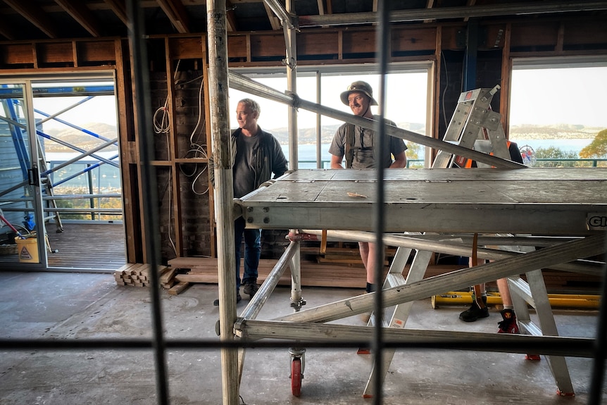 Two builders standing inside a house under construction