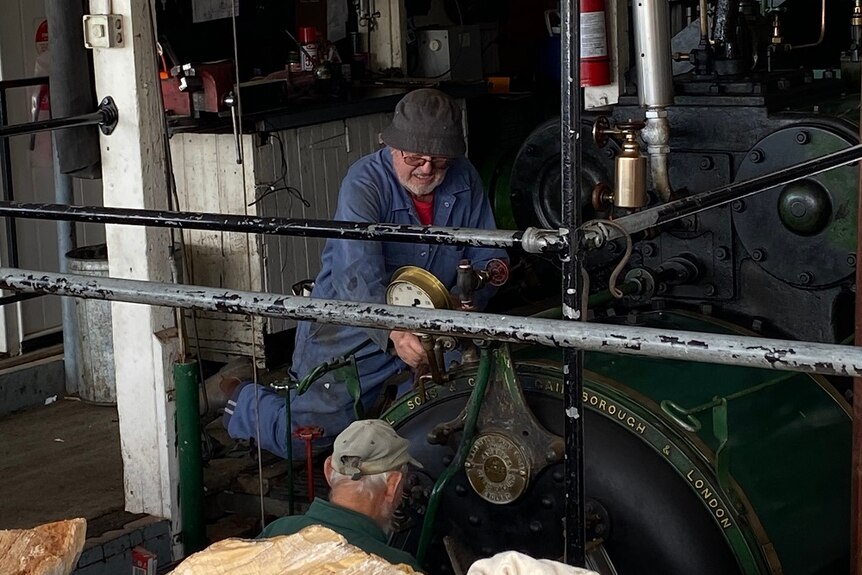 Two men repairing an engine on a paddle steamer.