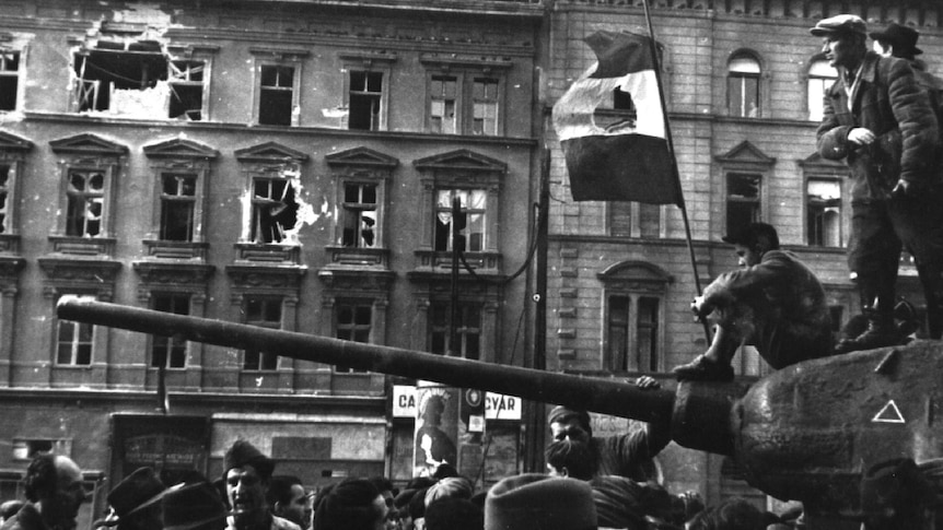 Fighters sit on top of a tank with a revolutionary flag in Budapest