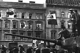 Fighters sit on top of a tank with a revolutionary flag in Budapest