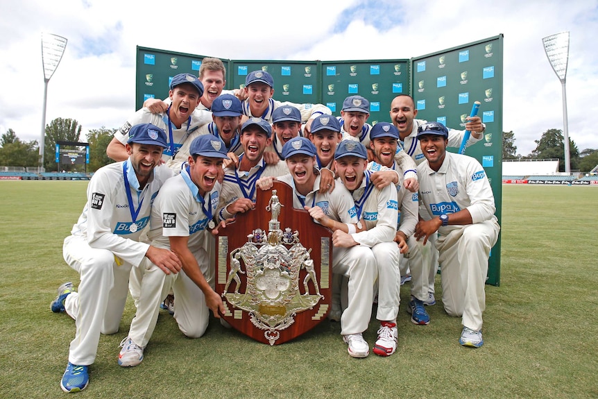 New South Wales players pose with the Sheffield Shield trophy after winning the title with a draw in the final against Western Australia