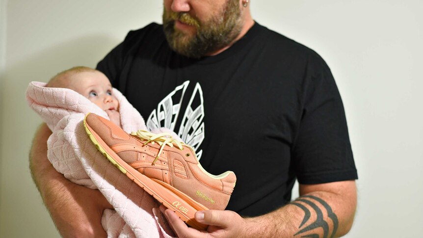 Lee Ingram and his baby daughter with a pair of pink sneakers