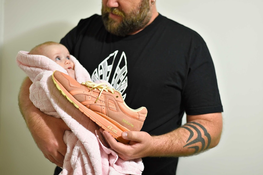 Lee Ingram and his baby daughter with a pair of pink sneakers