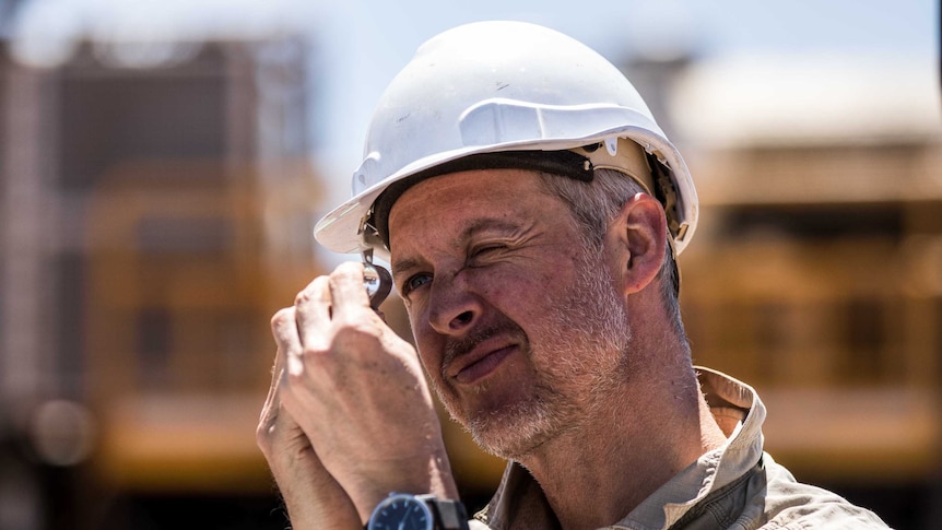 A geologist inspects rock chip samples under a magnifying glass