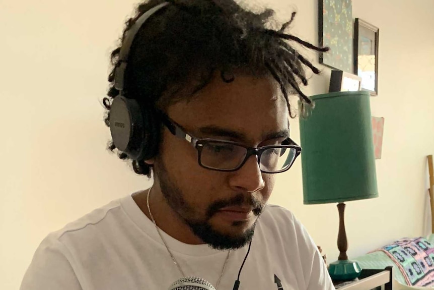 man wearing headphones in a home speaking into a microphone