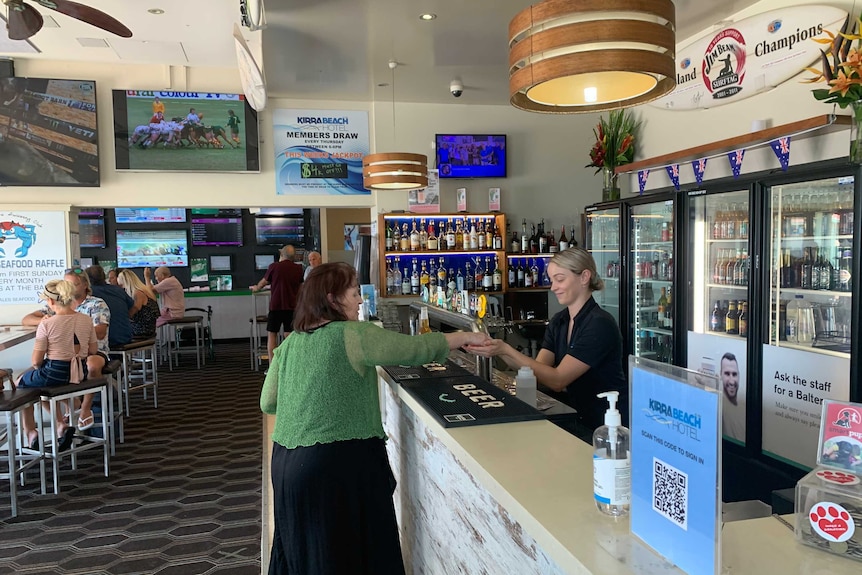 Barmaid serving customer in a bar.