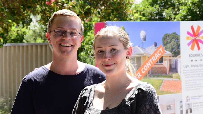 Dirk Black and Isabelle Southern stand outside their new home with a "under contract" sign in the background.