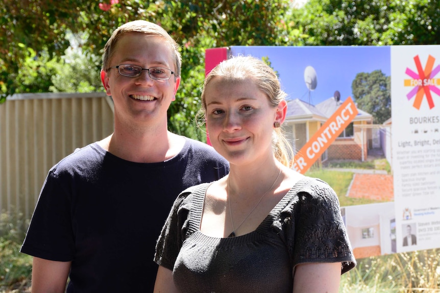 Dirk Black and Isabelle Southern stand outside their new home with a "under contract" sign in the background.