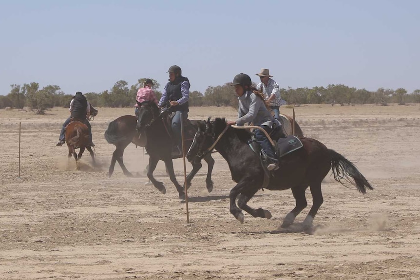 Horses run around a dusty race track