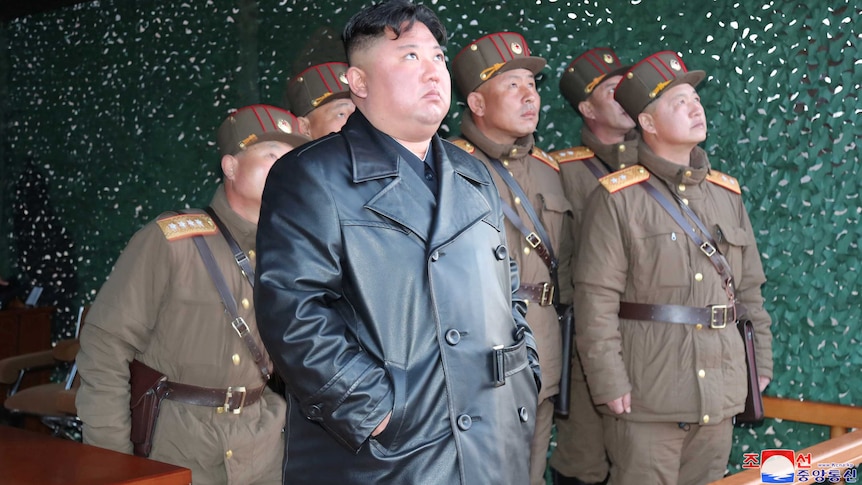 Kim Jong-un watches and his comrades look up into the sky.
