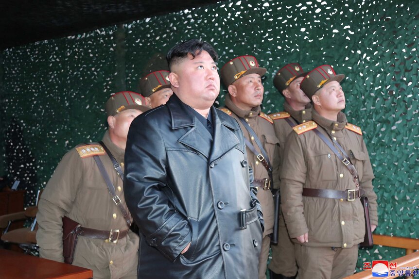 Kim Jong-un watches and his comrades look up into the sky.