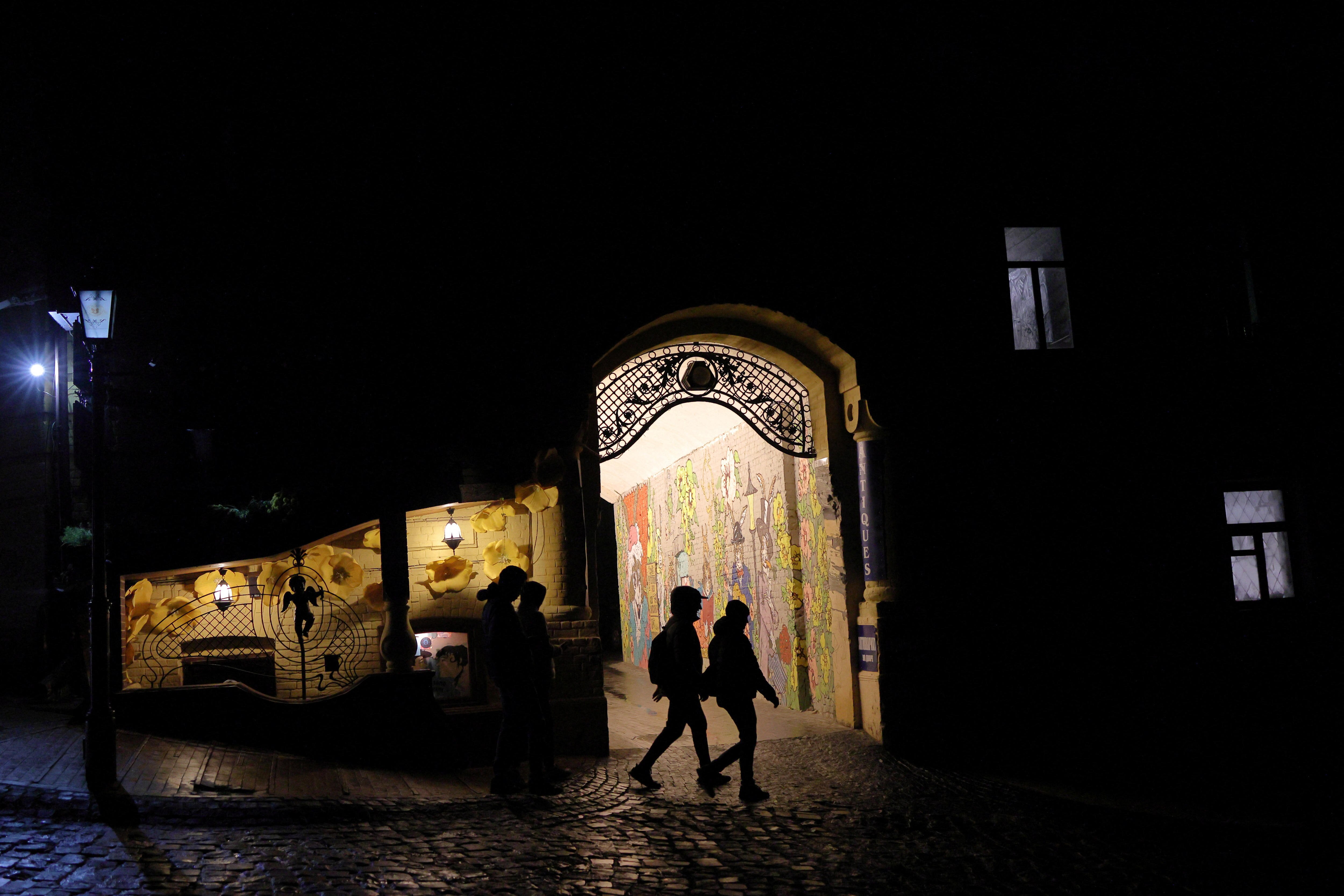 People walk on a dark street, as Russia's attack on Ukraine continues, in the old town of Kyiv.