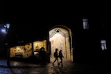 People walk on a dark street, as Russia's attack on Ukraine continues, in the old town of Kyiv.
