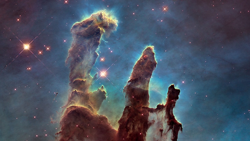 Huge, colourful gas clouds in space forming pillars and surrounded by stars