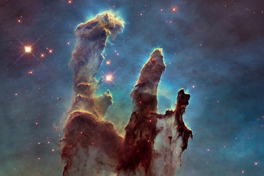 Huge, colourful gas clouds in space forming pillars and surrounded by stars