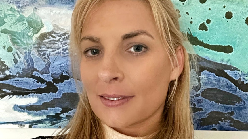 A woman with blonde hair smiles at the camera