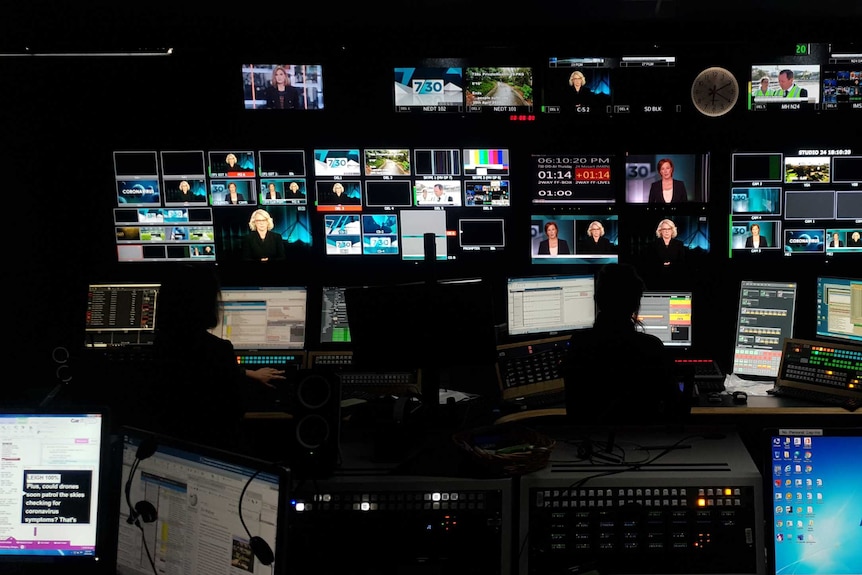 Wide shot inside studio control room with multiple TV monitors showing Leigh Sales and Laura Tingle on screen.