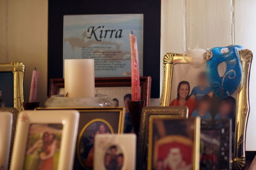 A variety of photo frames and candles on a mantle