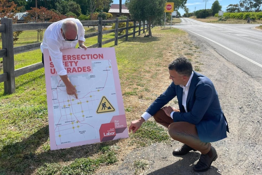 two man looking and pointing at a sign that has a map on it with the words Intersection Safety upgrades
