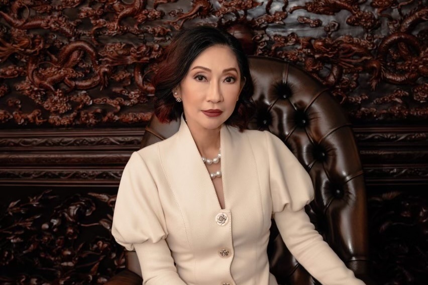 Dan Phuong Nguyen in a cream dress sitting on a leather chair. 