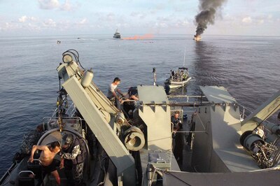 Asylum seekers aboard HMAS Albany as their boat burns in the distance, April 16 (ADF)