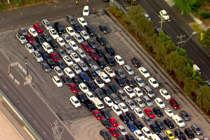 An aerial view of a drive-through COVID-19 testing site shows several rows of cars jammed together.