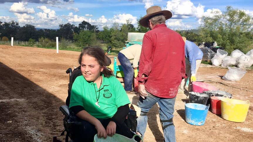 A girl in a wheelchair holding a green bucket