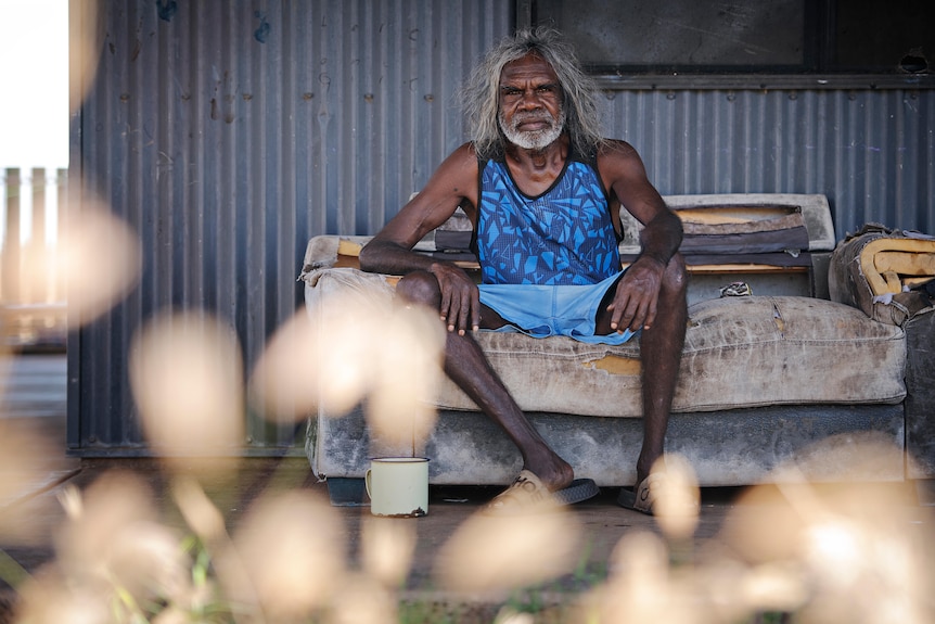 An Aboriginal man sits on a couch on his veranda