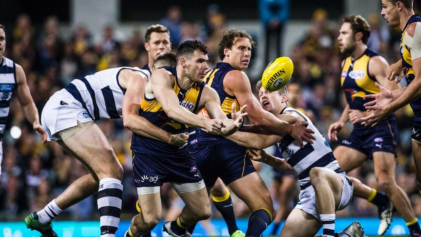 Luke Shuey handballs out of a tackle