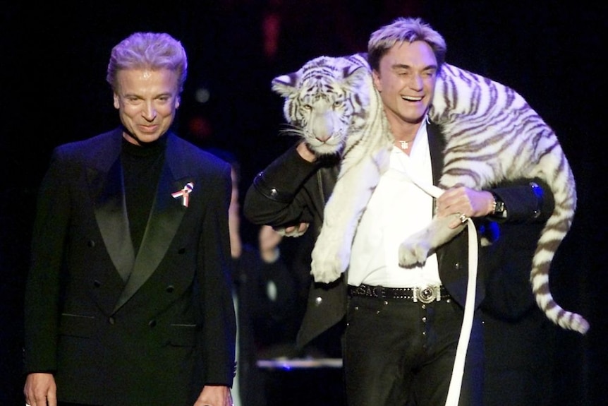 Two men onstage with a tiger