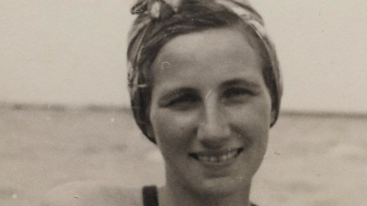 Black-and-white image of a smiling woman, with her hair tied in a wrap.
