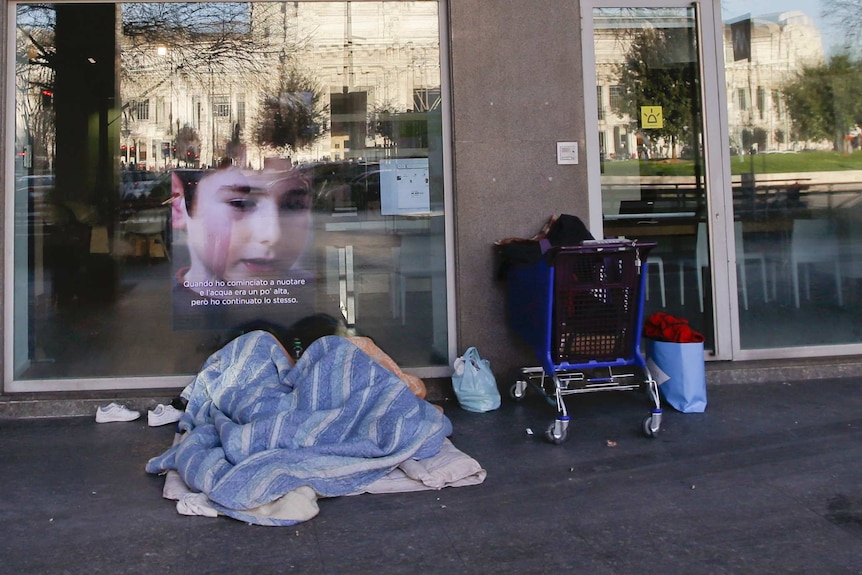 Homeless person sleeps under blanket in Italy