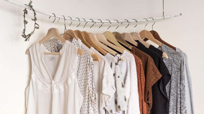 Different types of mostly female style blouses hang on floating rack.