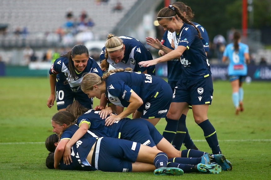 A group of Melbourne Victory players embrace as they celebrate a goal against Sydney FC.
