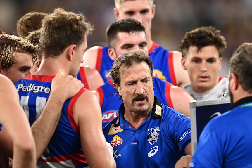 Players are huddled around Luke Beveridge as he speaks during a break