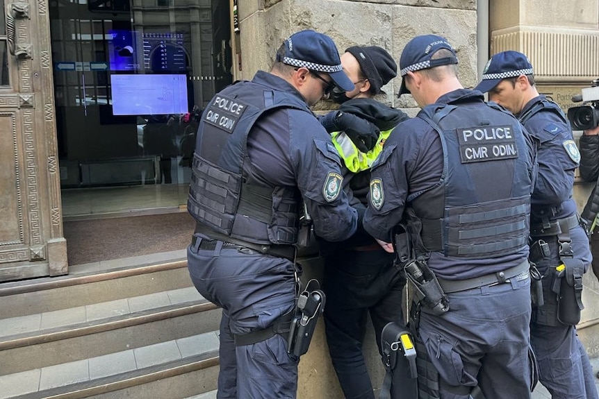 een persoon wordt vastgehouden terwijl politieagenten de persoon handboeien omdoen