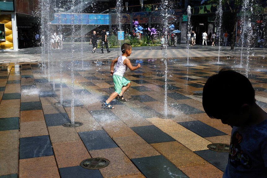A boy running through a water fountain. 