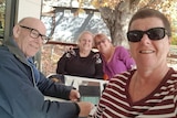 lady with short hair and sunglasses sitting at table with two other elderly women and elderly man