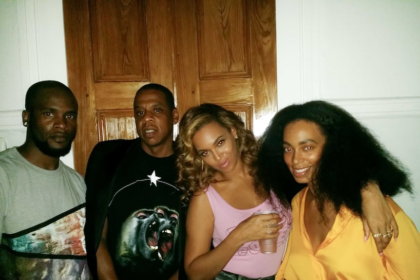 DJ Just Dizle, JAY-Z, Beyonce and Solange - two black men, two black women who have their arms around each other