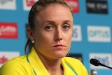 Sally Pearson sits behind a microphone during a press conference and stares seriously into the camera.
